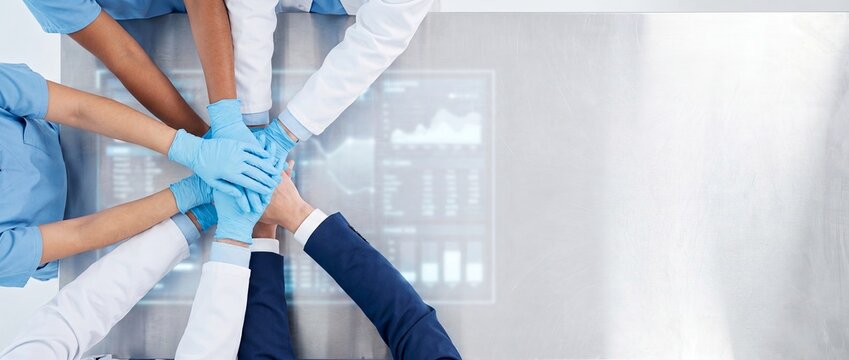 Top down view of medical professionals stacking hands over digital data screen