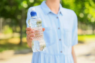Person holding plastic water bottle outdoors © Pixel-Shot