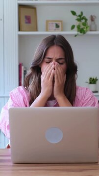 Young woman feeling shocked and desperate while looking at her laptop screen, crying and showing frustration after reading terrible news or experiencing a system failure at home