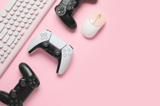 Gaming controllers and computer peripherals on pink background