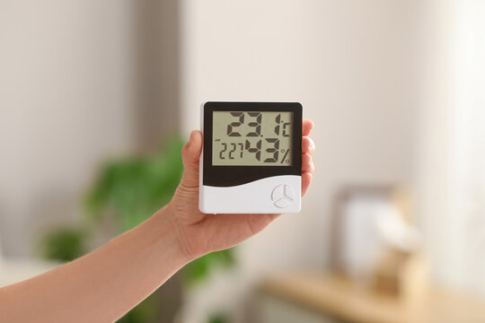Hand holding digital indoor thermometer and hygrometer