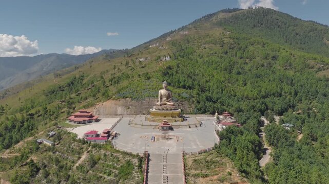 Aerial view of the massive golden Buddha Dordenma statue situated on a mountain ridge surrounded by lush green forests in Thimphu, Thimphu, Bhutan.