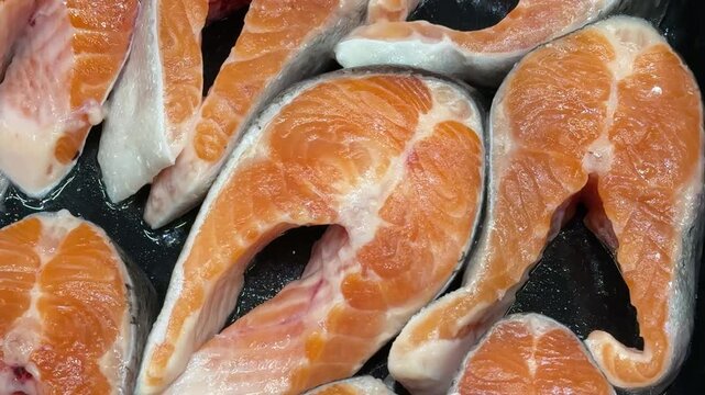 Steaks of chilled Atlantic salmon from frozen raw materials on a substrate for sale in a supermarket. Close-up