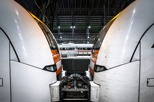 Trains stand on platforms inside Koln Hbf, Cologne Main train station in Germany with a regional train and high speed train visible in the railway station under the arched roof in a busy transport hub