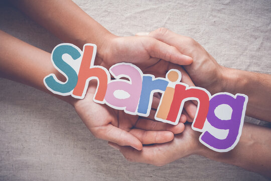sharing, hands, support, kindness, community, generosity, care. Conceptual image of adult and child hands cupping the word sharing for empathy, charity, and social connection.
