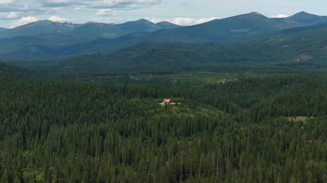 Wide Aerial of secluded cabin in Idaho Panhandle in Bonner County in summer with dense Kaniksu national forest and mountains
