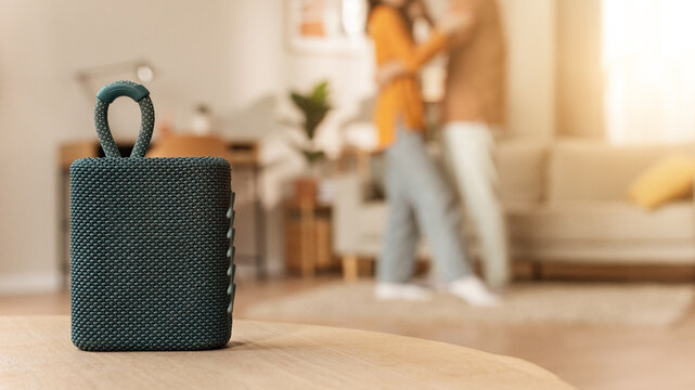 Happy Unrecognizable Young Couple Embracing Each Other At Home In Living Room With Bluetooth Speaker On Table, Enjoying Quality Time Together, Creating A Warm And Cozy Atmosphere. Lifestyle Concept