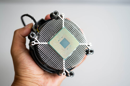 Hand holding computer processor on CPU air cooler for PC assembly, semiconductor technology and hardware upgrade. Concept of computer building, processor installation and high performance computing.