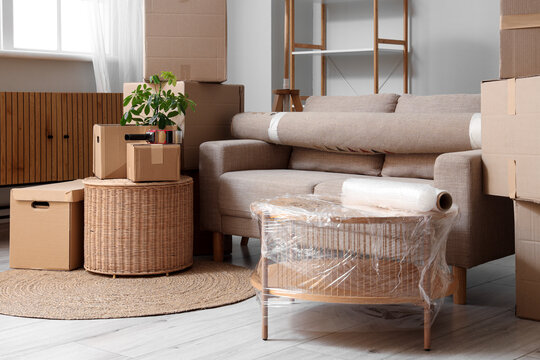 Living room with packed moving boxes and wrapped furniture