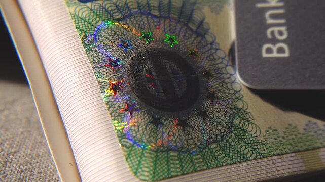 A close-up of the illuminated holographic emblem of the EU Schengen visa. The iridescent multicolor security hologram of the Schengen visa of the European Union countries. 4k slow motion video 60 fps.