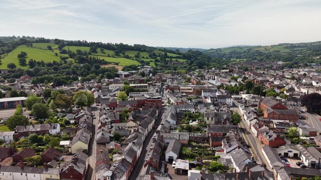Cinematic aerial drone footage showcasing the historic market town of Tiverton in Devon, England. The flight captures the town, residential neighborhoods, architecture, surrounding countryside