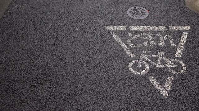 Right-positioned close-up of bicycle stop pavement marking on wet sidewalk in Japan on a light rainy morning