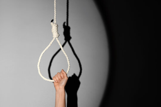 Female hand and hanging rope with loop on grey background. Suicide concept