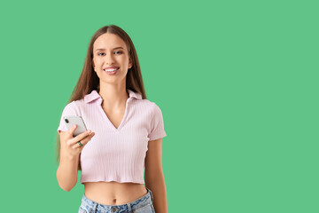 Naklejka premium Beautiful young woman with modern mobile phone on green background
