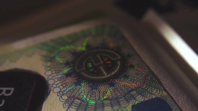 A close-up of the illuminated holographic emblem of the EU Schengen visa. The iridescent multicolor security hologram of the Schengen visa of the European Union countries. 4k slow motion video 60 fps.