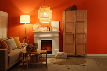 Obraz premium Fireplace with sofa, closet and glowing lamps near orange wall in living room