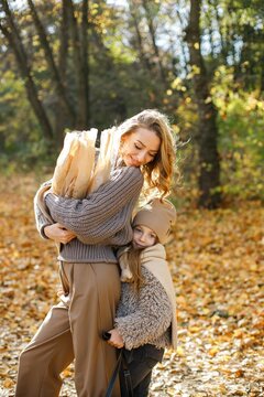 Fashionable young mother with a little daughter in autumn park