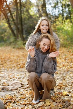 Fashionable young mother with a little daughter in autumn park