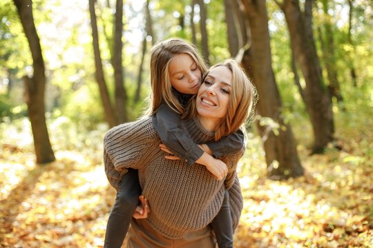 Fashionable young mother with a little daughter in autumn park