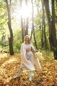 Portrait of a curly woman with yellow flowers outdoors in autumn park