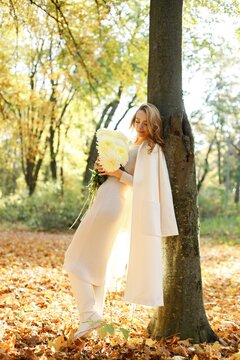 Portrait of a curly woman with yellow flowers outdoors in autumn park