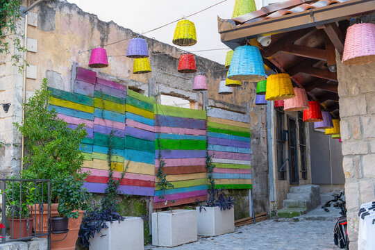 Colorful hanging fabric lamp shade decorating an outdoor street alley with stone building and striped textile, festive decor.