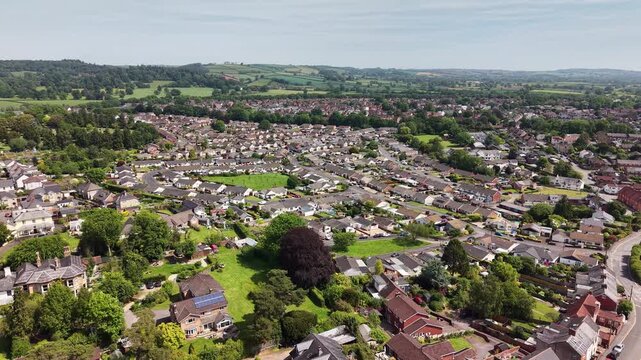 Cinematic aerial drone footage showcasing the historic market town of Tiverton in Devon, England. The flight captures the town, residential neighborhoods, architecture, surrounding countryside
