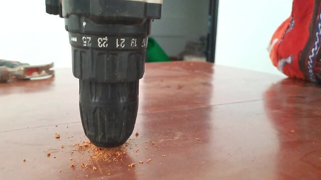 Technician drilling wooden library table with power drill for electrical outlet installation. Worker assembling socket wiring. Construction stock video 4K for DIY, renovation, carpentry, maintenance, 