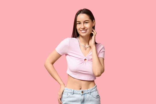 Beautiful young happy woman with piercing navel on pink background