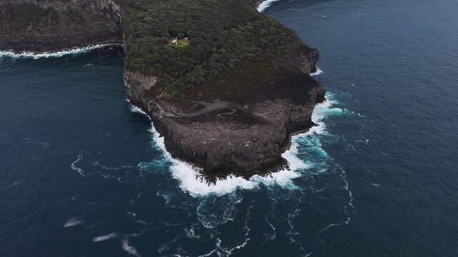 Aerial view of Miradouro da Ponta do Queimado cliff surrounded by deep blue Atlantic ocean waters in Serreta, Acores, Portugal.