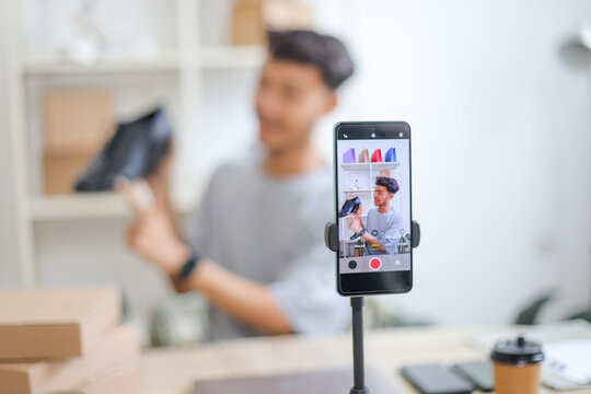 Smartphone on Ring Light Recording male Blogger Live Streaming and Selling Shoes Online in Studio