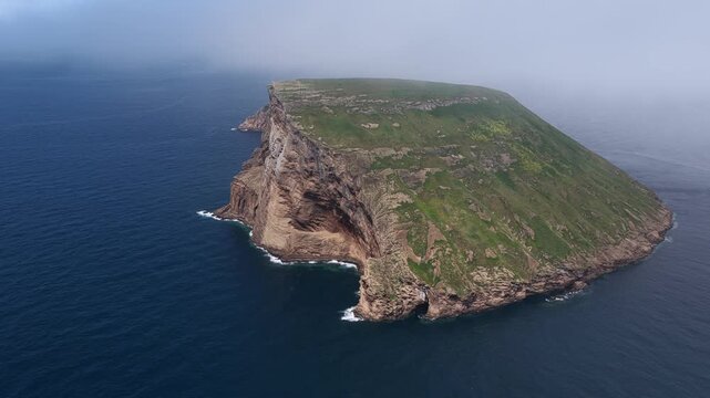 Aerial view of Ilheus das Cabras, a rugged volcanic islet surrounded by deep blue Atlantic waters in the Azores, Portugal.