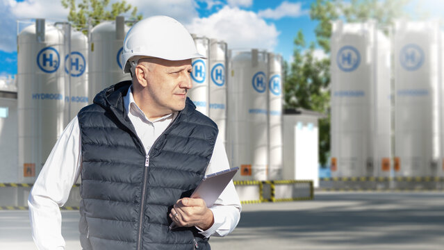 Hydrogen production plant inspection engineer reviews operations at hydrogen storage facility using tablet in industrial energy site.