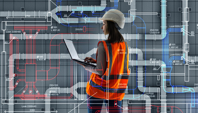 Industrial piping engineering design review engineer uses laptop while analyzing complex HVAC and pipeline schematics in construction planning environment