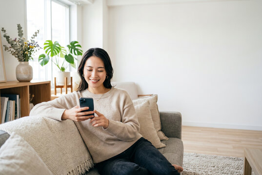 ソファでスマホを見て微笑むリラックスした女性 Generative AI