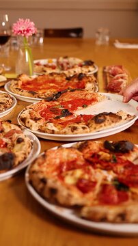 Friends Sharing Neapolitan Pizzas at a Large Restaurant Dining Table