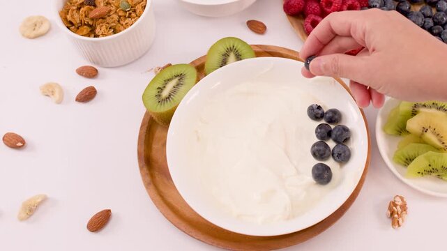 Adding Fresh Blueberries to a Greek Yogurt Breakfast Bowl