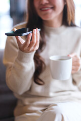 Fototapeta premium Vertical closeup of a woman holding smart phone and using voice messaging, talking with ai assistant for Artificial intelligence concept