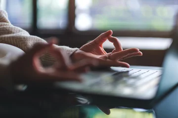 Fototapeten Lotusblume Closeup image of a woman hands in lotus pose over laptop computer for stress relief concept  © Farknot Architect