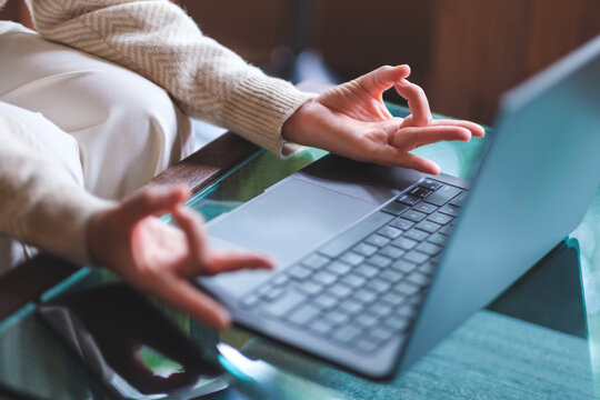 Closeup image of a woman hands in lotus pose over laptop computer for stress relief concept