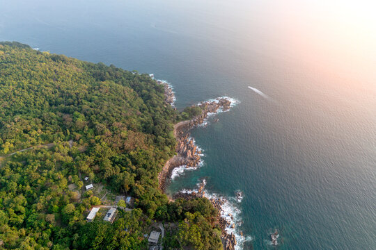 Golden sunset light illuminates the tropical jungle landscape and Andaman Sea coastline in Phuket, Thailand