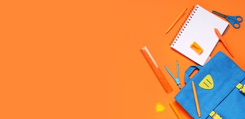 School supplies on orange background with blue backpack