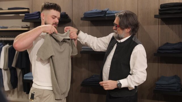 Shop assistant helping a customer choose a polo shirt