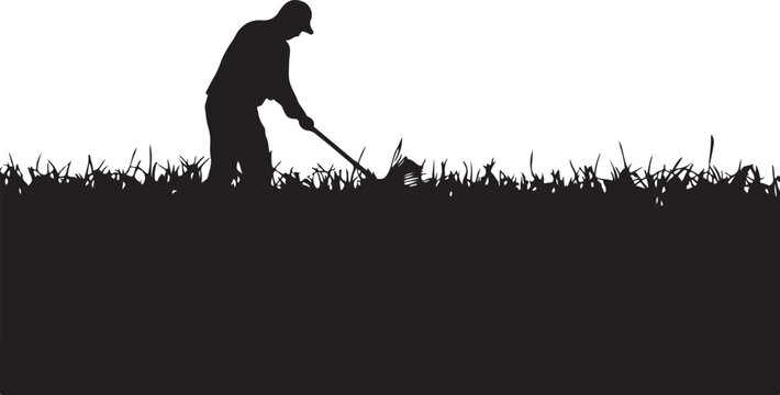 Silhouette of a man mowing grass with a push lawn mower