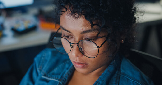 Close-up young Black female programmer coding AI software on multiple screens in night office. Network security, cybersecurity, machine learning, working late, overtime, robotics automation concept.