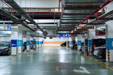 Naklejka premium Underground parking garage with cars and directional signs