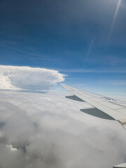 Naklejka premium View from an airplane window looking out over beautiful clouds and blue sky during flight.