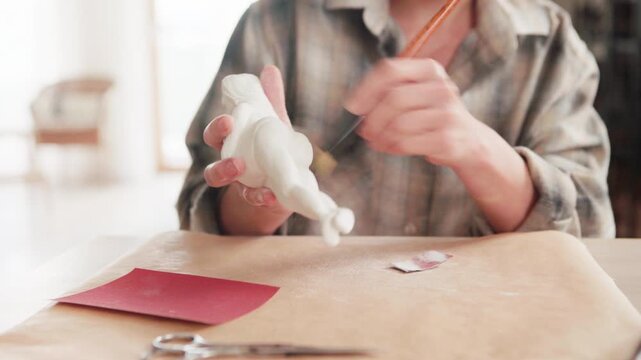 Close up of female hands polishing clay sculpture with sandpaper in 4K. Hobby sculptor sanding ceramic figurine to smooth surface in bright art studio workshop. Craft and DIY concept.