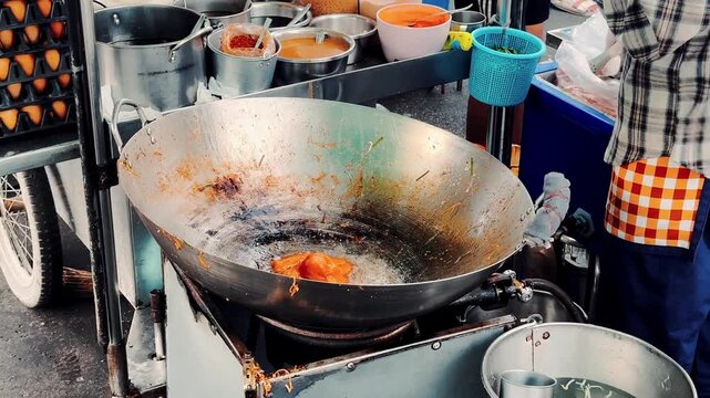 Close up of chef stirring and frying noodles with bean sprouts in a giant wok, authentic Thai street food.