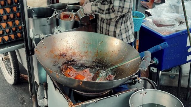 Close up of chef stirring and frying noodles with bean sprouts in a giant wok, authentic Thai street food.